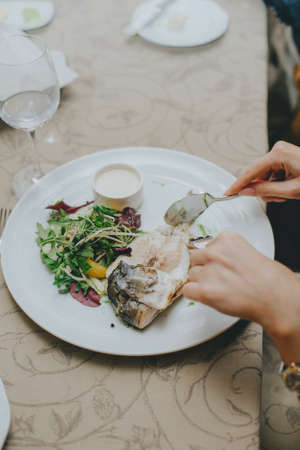 hands close up with etiquette cutlery. Eating a fish dish close up. Table etiquette.の写真素材