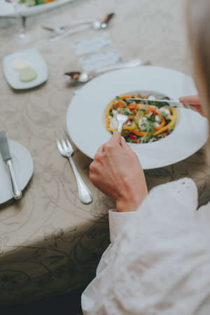 There is a salad close-up. hands properly hold cutlery in the restaurant. table etiquette.の写真素材