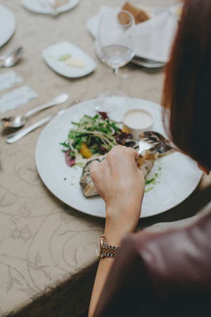 hands close up with etiquette cutlery. Eating a fish dish close up. Table etiquette.