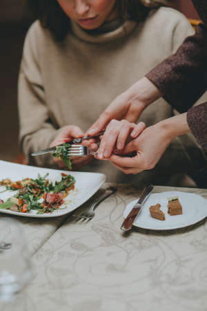 There is a salad close-up. hands properly hold cutlery in the restaurant. table etiquette.の写真素材