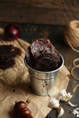 Homemade beef jerky seasoned with garlic, onion, pepper and salt. Jerky in a bucket on a wooden backgroundの写真素材