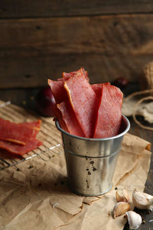 Homemade beef jerky seasoned with garlic, onion, pepper and salt. Jerky in a bucket on a wooden backgroundの写真素材