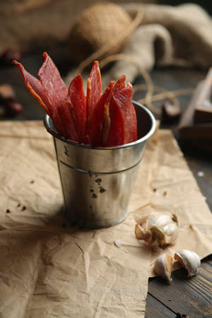 Homemade beef jerky seasoned with garlic, onion, pepper and salt. Jerky in a bucket on a wooden backgroundの写真素材