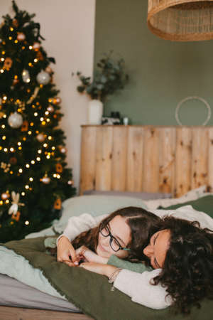 Happy young woman with cute teenage daughter in christmas interior on bed.の写真素材