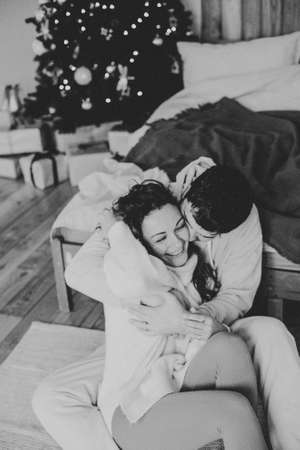 Young couple in a house in a romantic winter landscape in a christmas interiorの写真素材