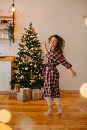 beautiful young woman dancing in a christmas inerie on the background of a christmas treeの写真素材