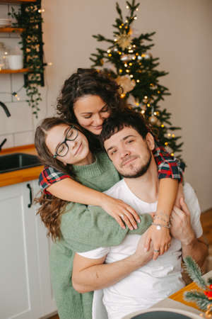 young family mom dad and teenage daughter on background of christmas interiorの写真素材