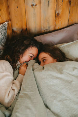 Happy young woman with cute teenage daughter posing in bed