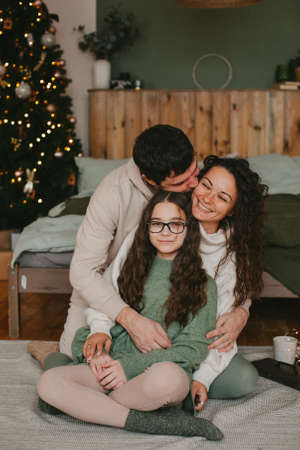 young family mom dad and teenage daughter on background of christmas interiorの写真素材