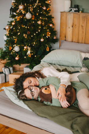 Happy young woman with cute teenage daughter in christmas interior on bed.の写真素材