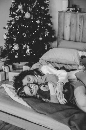 Happy young woman with cute teenage daughter in christmas interior on bed.の写真素材