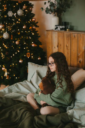 happy teenage girl sitting near christmas treeの写真素材