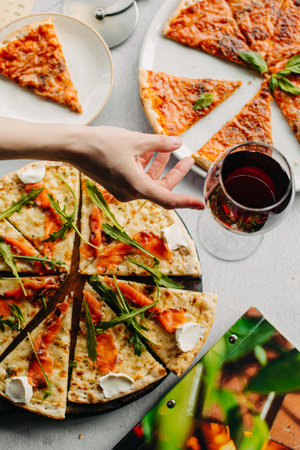 Traditional Italian pizza, vegetables, ingredients on a light background.Top view. a piece of pizza in the hand.Festive table. company of friendsの写真素材