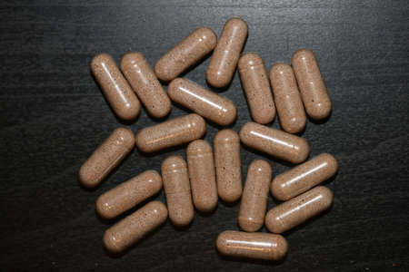 Transparent capsules filled with brown vitamins powder close up background high quality big size printの写真素材