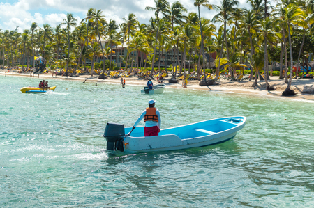 The rescue boat and the people relaxing on the beach among palm trees in the resort of Punta Cana.のeditorial素材