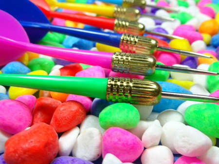 Pink, red, blue, yellow and green darts on colourful stone background