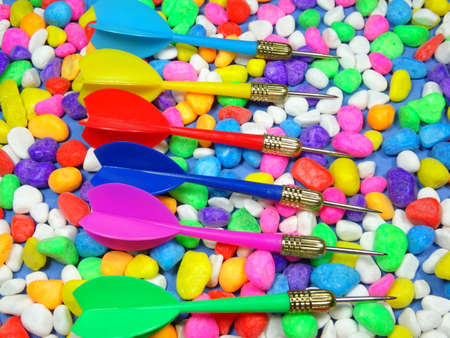 Pink, red, blue, yellow and green darts on colourful stone backgroundの写真素材