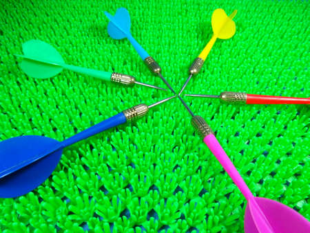 blue, pink, red, yellow and green darts on artificial green grass backgroundの写真素材