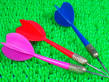 Red, blue and pink dart on artificial green grass background