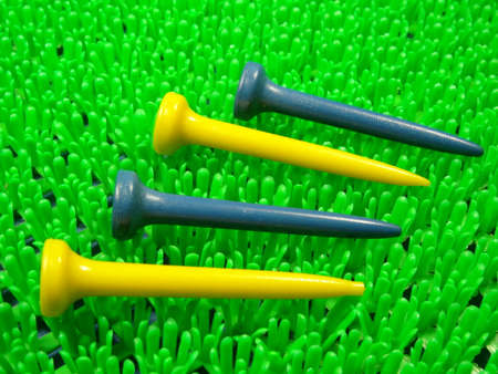 golf  ball blue and yellow tees on artificial green grass backgroundの写真素材