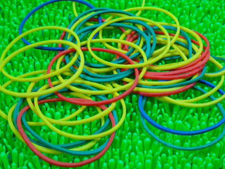 colourfull rubber bands on artificial green grass backgroundの写真素材