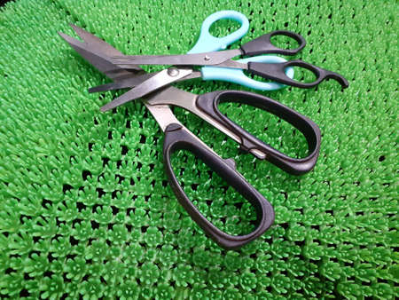 A blue scissor on artificial green grass background. photo taken in Malaysia