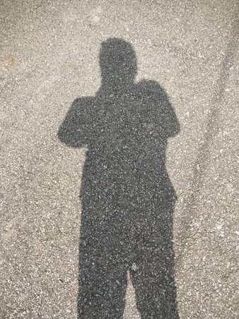 Shadow of a man standing on asphalt road. Shallow depth of field. photo taken in malaysiaの写真素材