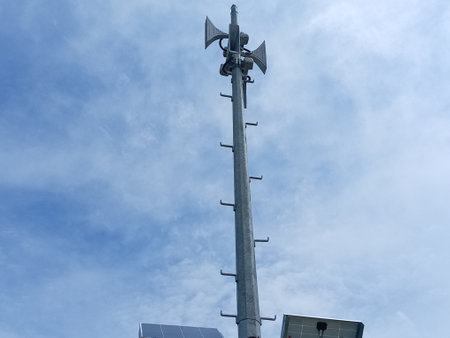 Solar powered flood alert siren pole with blue sky and white cloud background in the...