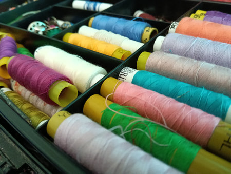 Vibrant spools of colorful stitching threads organized neatly in a sewing kit, emphasizing craft and...