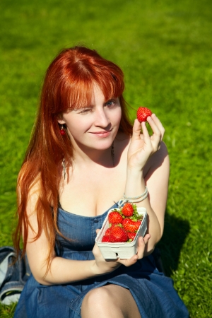 Beautiful girl pick up a strawberry from a bowlの写真素材