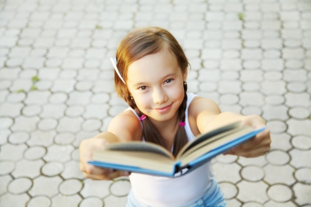 cheerful girl holds out a book ahead, focus on the eyesの写真素材