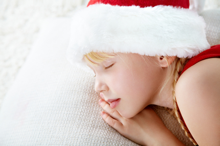 portrait of a sleeping girl in a Santa hatの写真素材