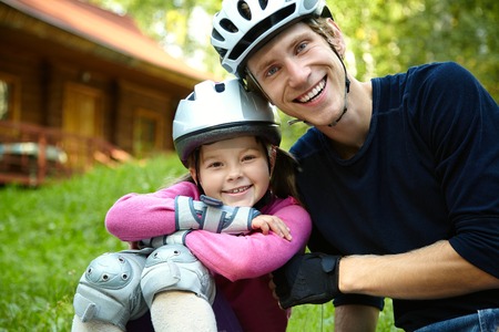 portrait of a sports dad and daughter in a helmet. Dad with his little daughter on the skatesの写真素材
