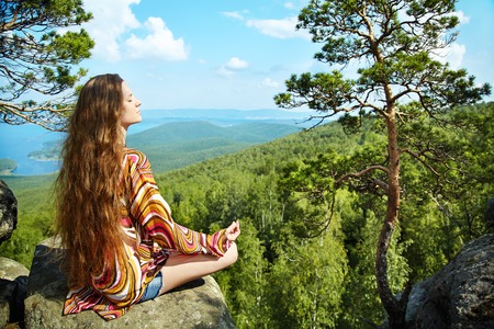 Young beautiful woman meditating at the mountainsの写真素材