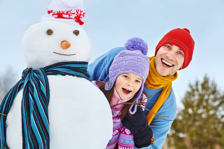 funny dad and daughter with a snowman in winterの写真素材