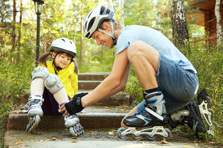 portrait of a sports dad and daughter in a helmet. Dad with his little daughter on the skatesの写真素材