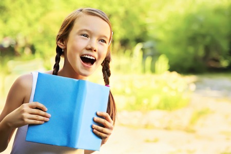 portrait of a emotional girl holding a book on green background. reading, learning and educationの写真素材