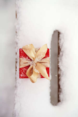 red winter Christmas gift box in the snow outdoorsの写真素材