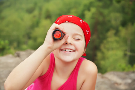 funny little girl in a bandana with a spyglass. children outdoorsの写真素材