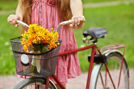 young woman with a bike in the park . flowers in a basket. Outdoorsの写真素材