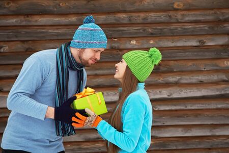 Young happy couple in love outdoors in the winter. a man gives gift to a woman