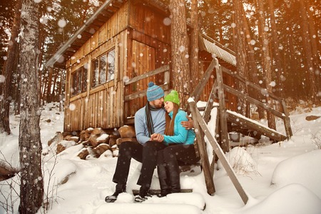 man and woman sitting on the porch of a house. young happy couple in love outdoors in the winterの写真素材