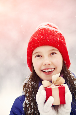 Pretty teenage girl with red gift in her hands. adolescent winter outdoorsの写真素材
