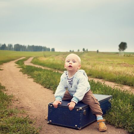 child sitting on a suitcaseの写真素材