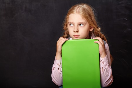 schoolgirl with a book on blackboard background