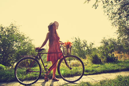 young woman in a hat with a bike in a parkの写真素材