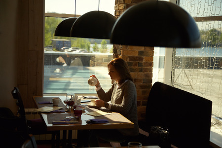 pretty young woman sitting in a cafe with cup of tea