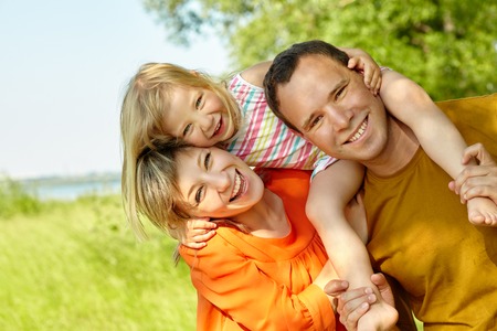 portrait of a happy playing family outdoors. parents with daughter in the summer. Mom, dad and childの写真素材