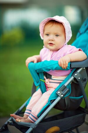 little girl in a stroller. baby for a walk in a pram. child in summer outdoorsの写真素材