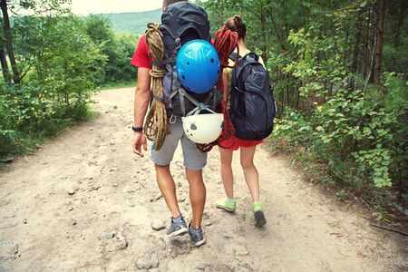 Young couple hikers in a forest. sports man and woman with backpacks on road in natureの写真素材